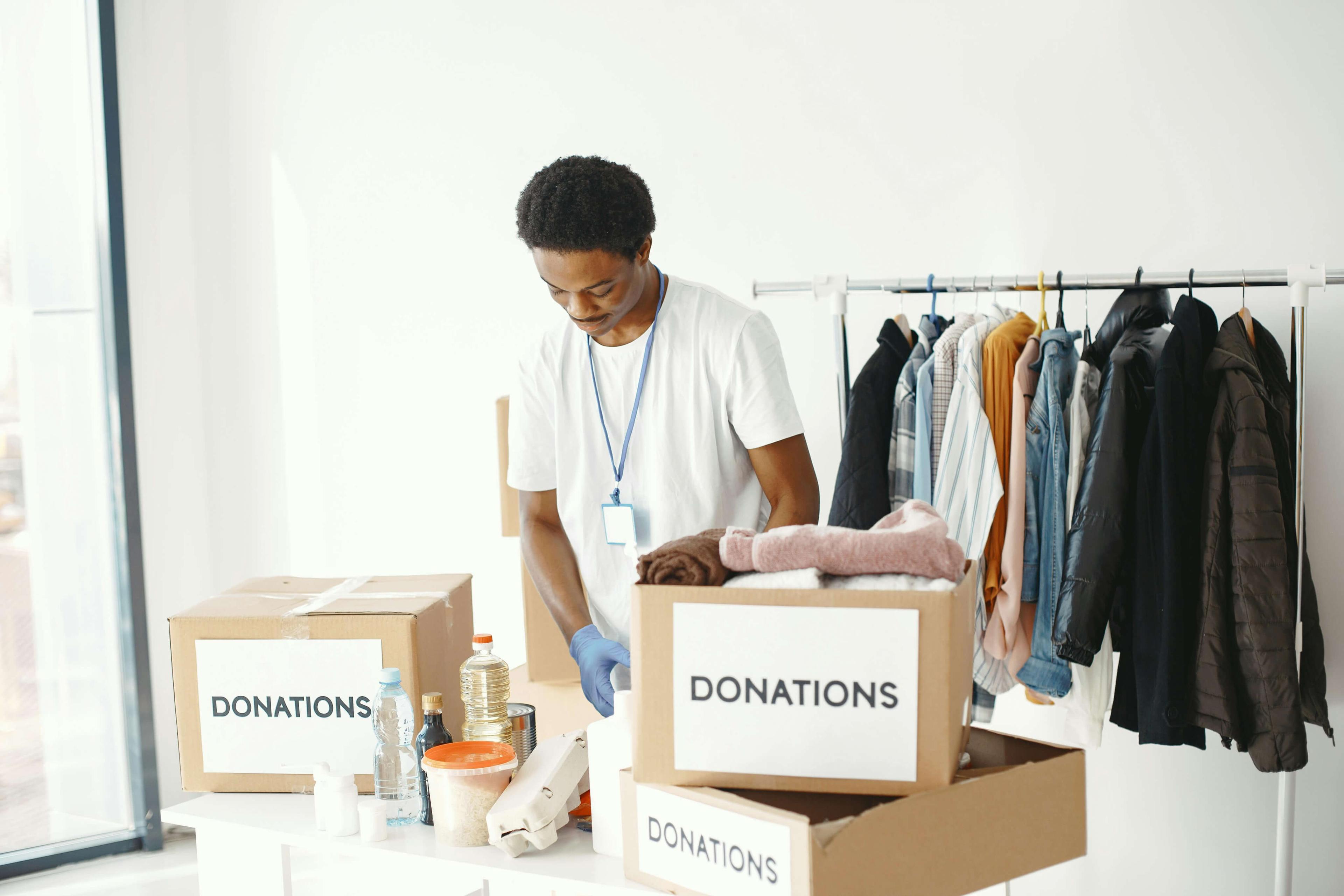 Man sorting donation boxes with clothing rack