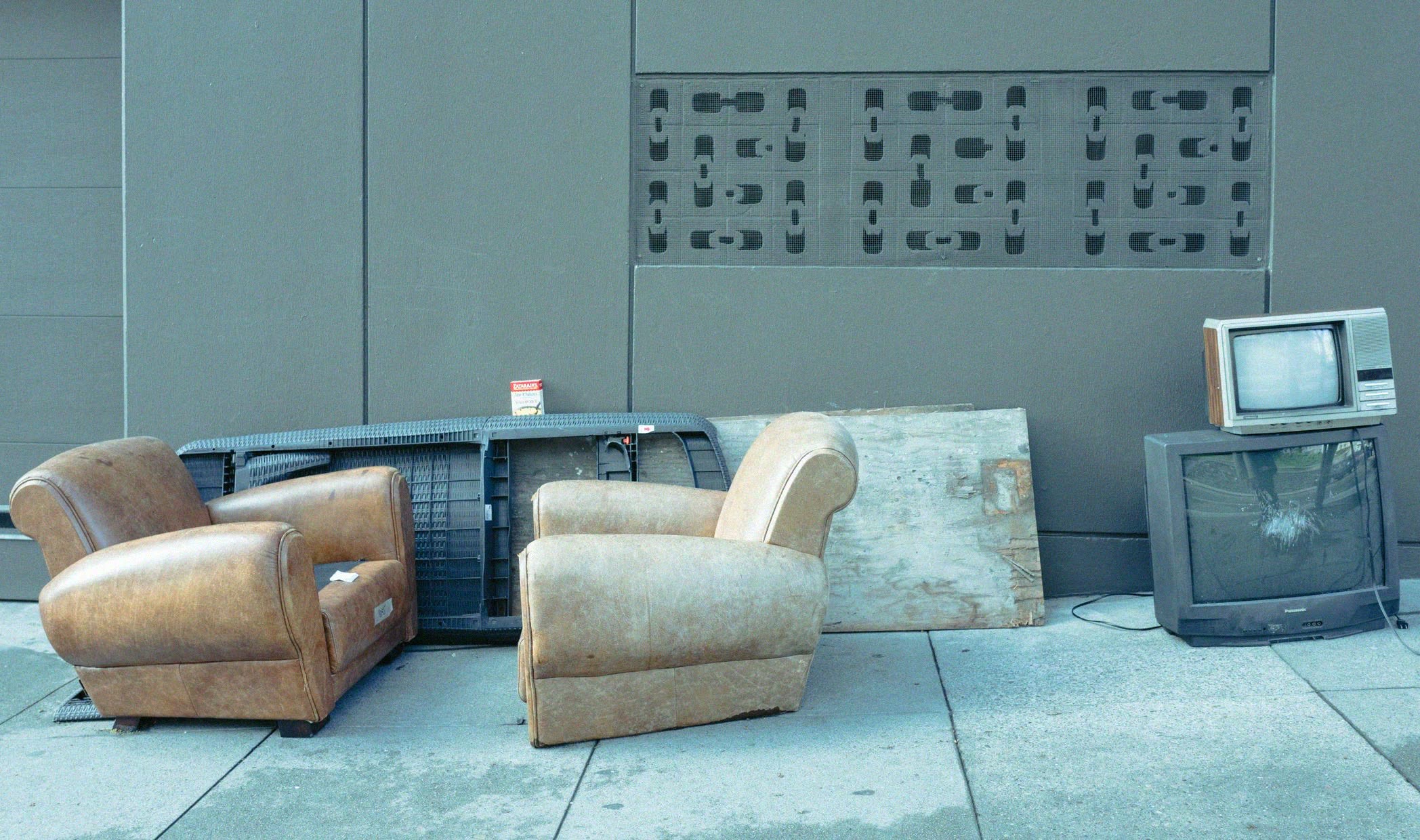Bulky armchairs and old TVs left out on a sidewalk for pickup